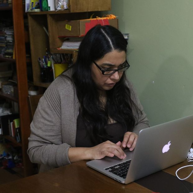 Un mujer realiza home office, mientras que su hijo juega
